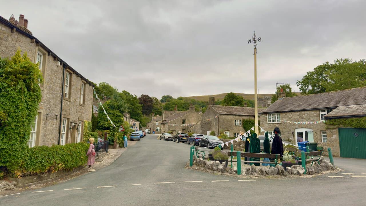 The maypole at the Kettlewell crossroads, with stone cottages and scarecrows lining the village street.