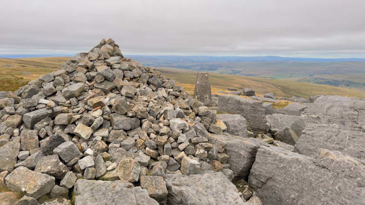 The stone cairn standing beside the triangulation pillar on the summit of Great Whernside.