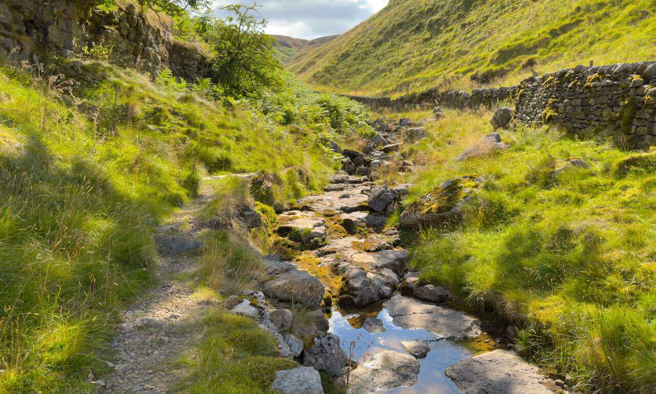 The dry bed of Dowber Gill Beck, with shallow pools sitting between the limestone slabs.