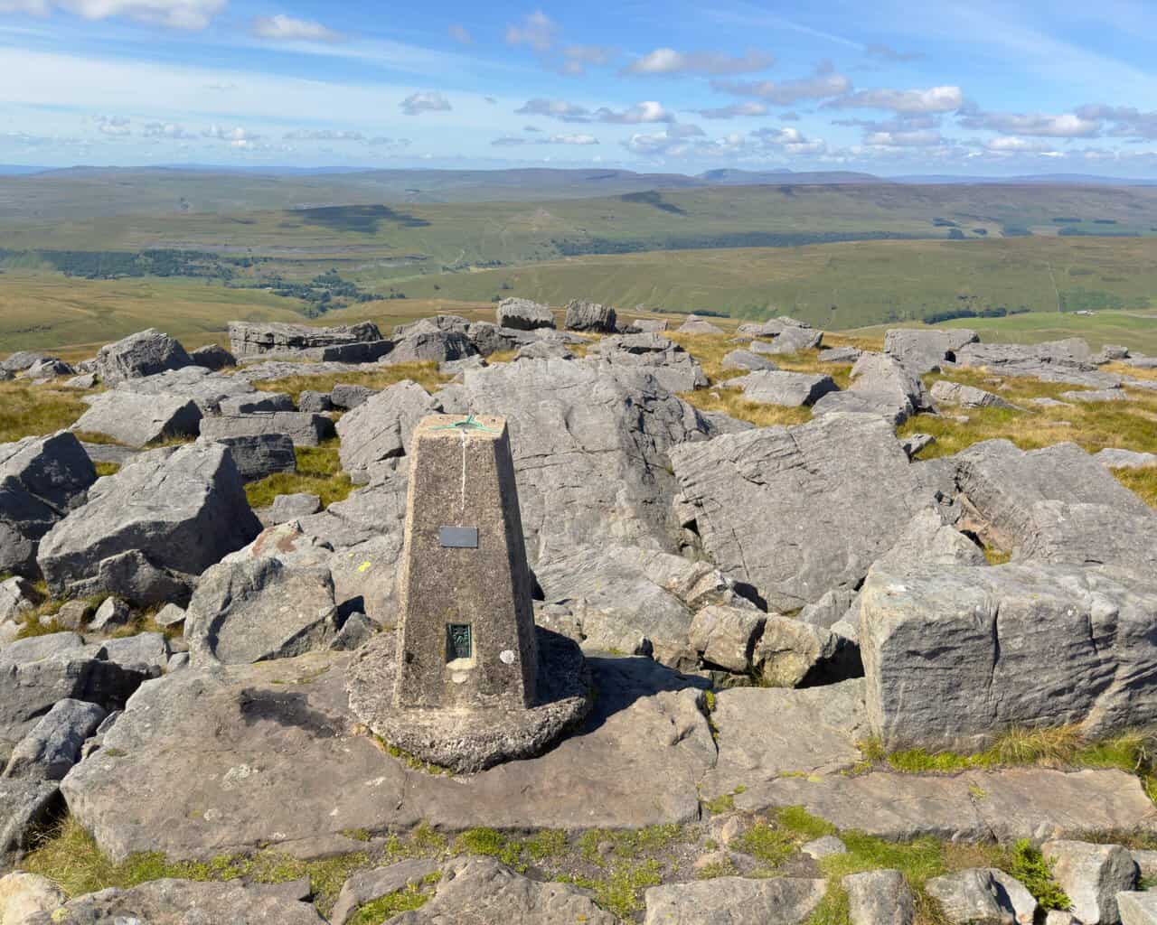 Views west from the summit towards the distant outlines of Pen-y-ghent, Ingleborough and Whernside.