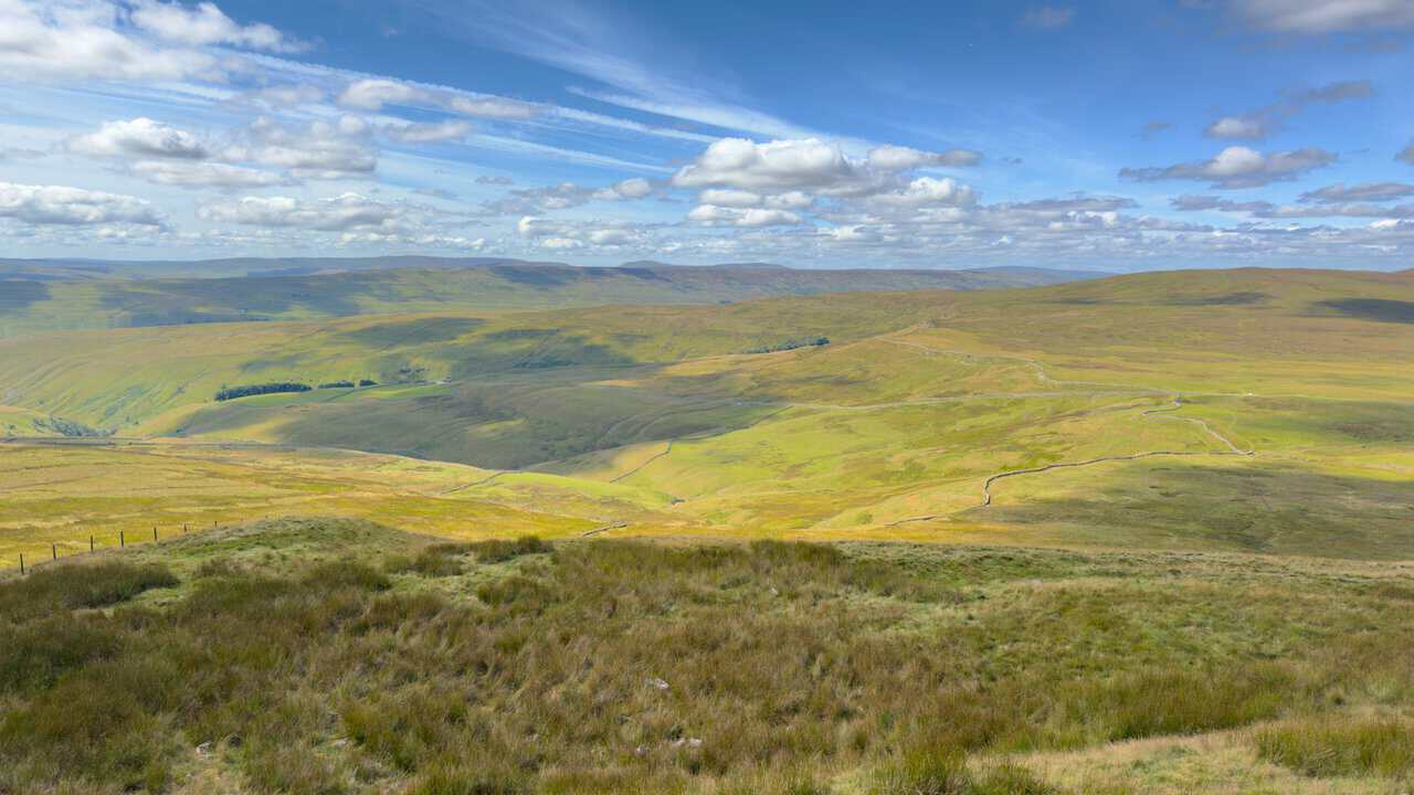 Rolling moorland stretching away to the horizon as the path loses height across the ridge.