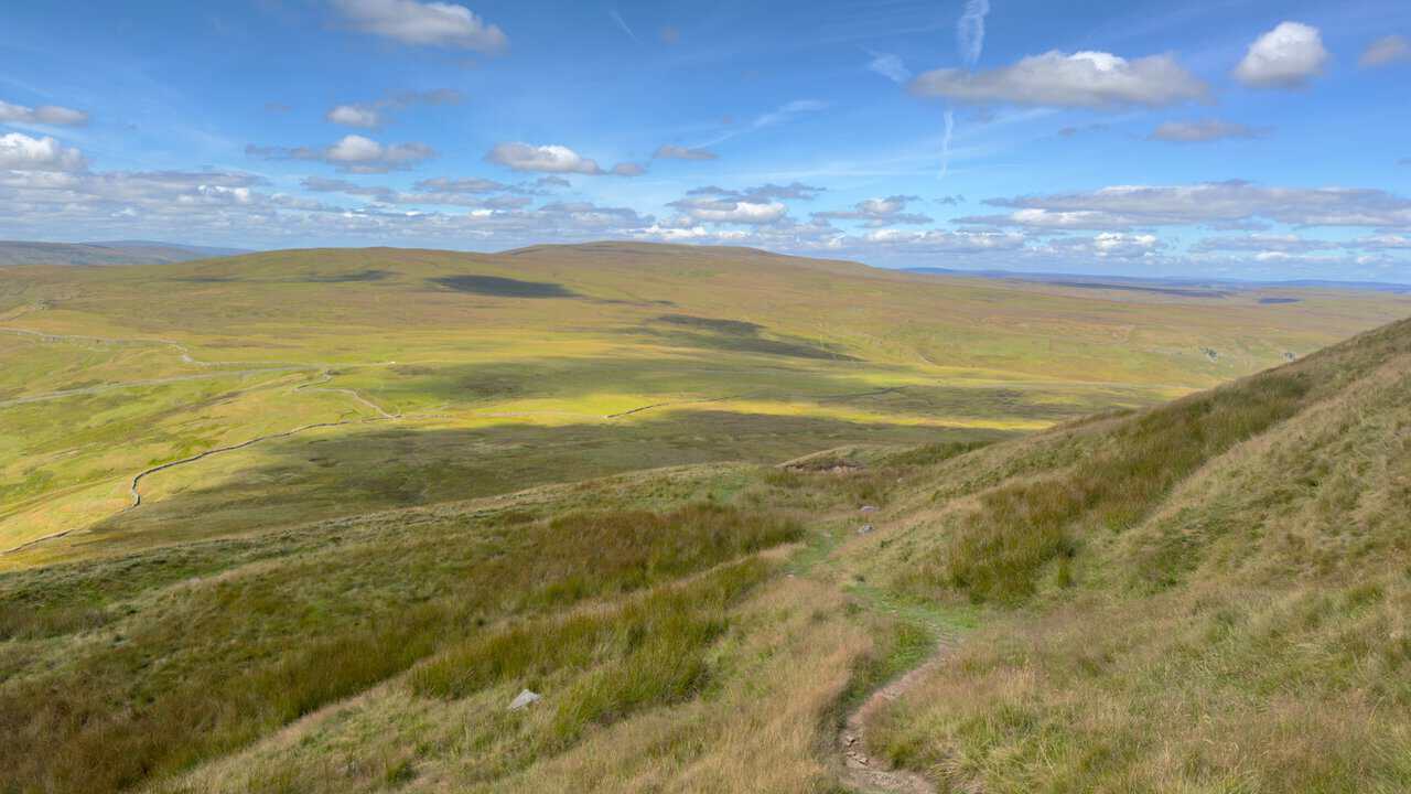 The path dropping steeply after Black Dike Hole, with sunlit moorland spreading out below.