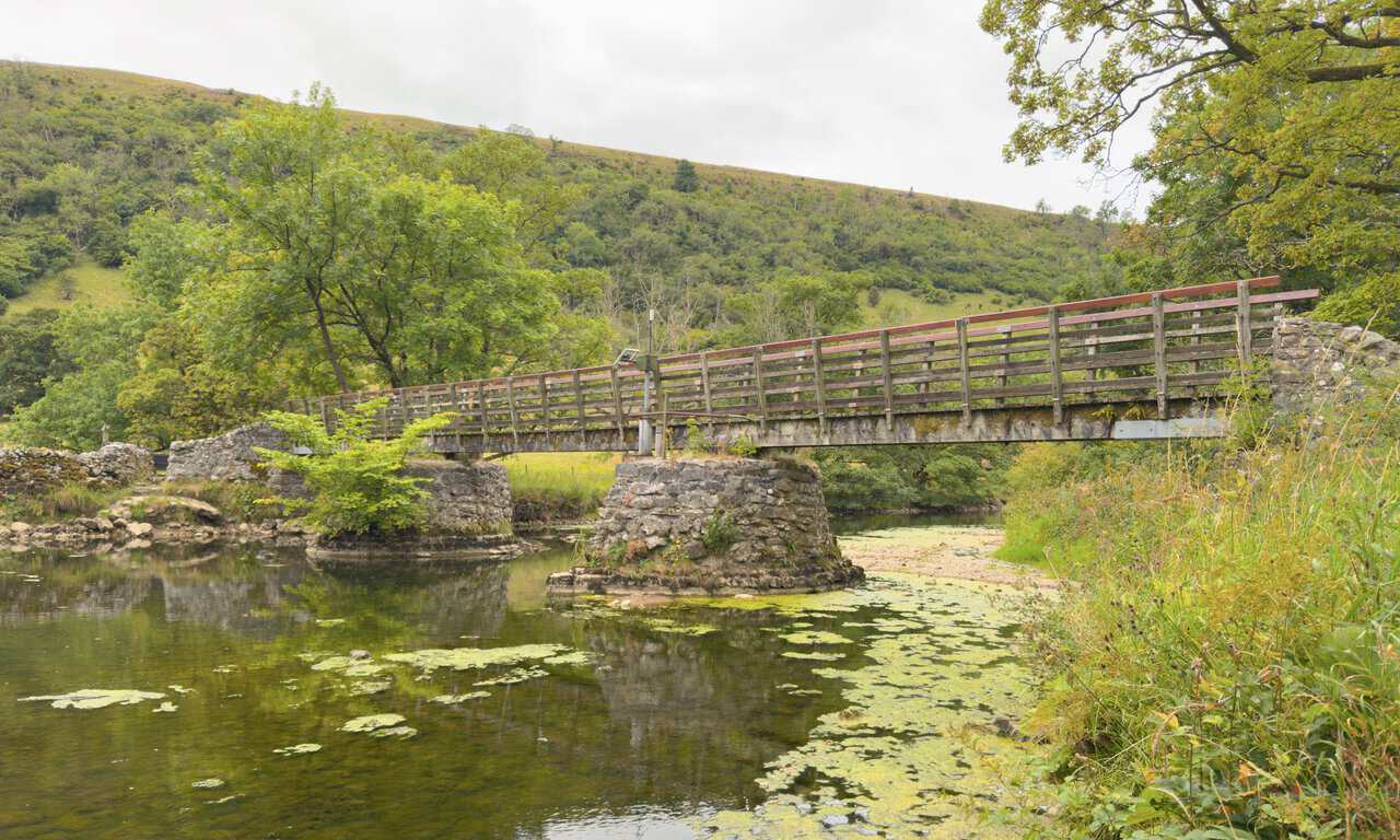 The wooden footbridge on stone piers carrying the path over the River Wharfe near Starbotton.