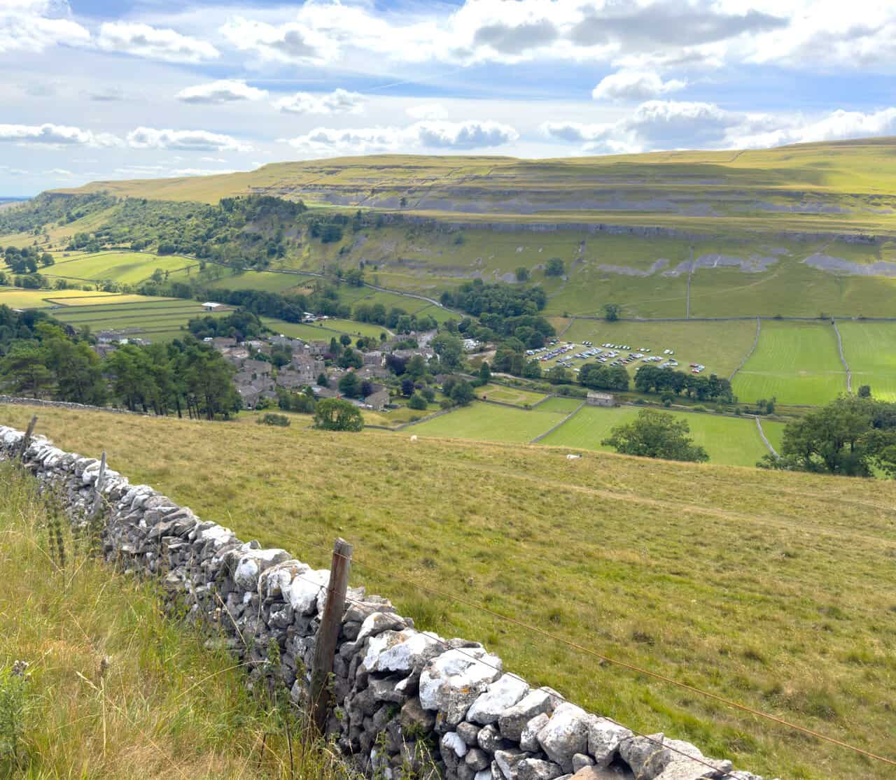 Kettlewell seen from above, with a field turned over to parking and filled with cars for the Scarecrow Festival.