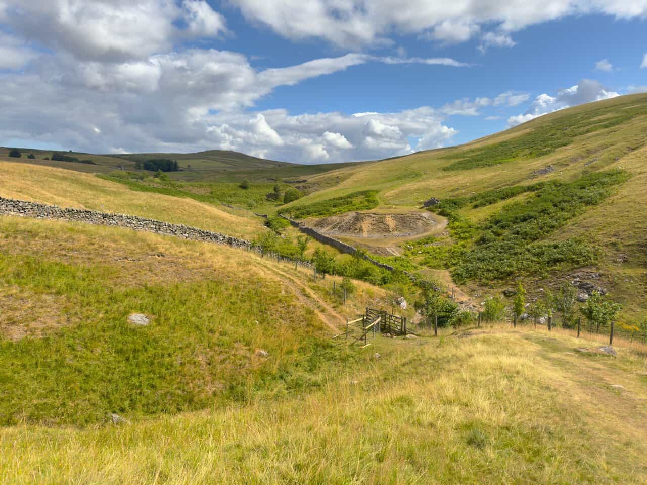 Looking down from Gill Heads towards the footbridge, with the pale spoil of the old lead and fluorspar mine beyond.