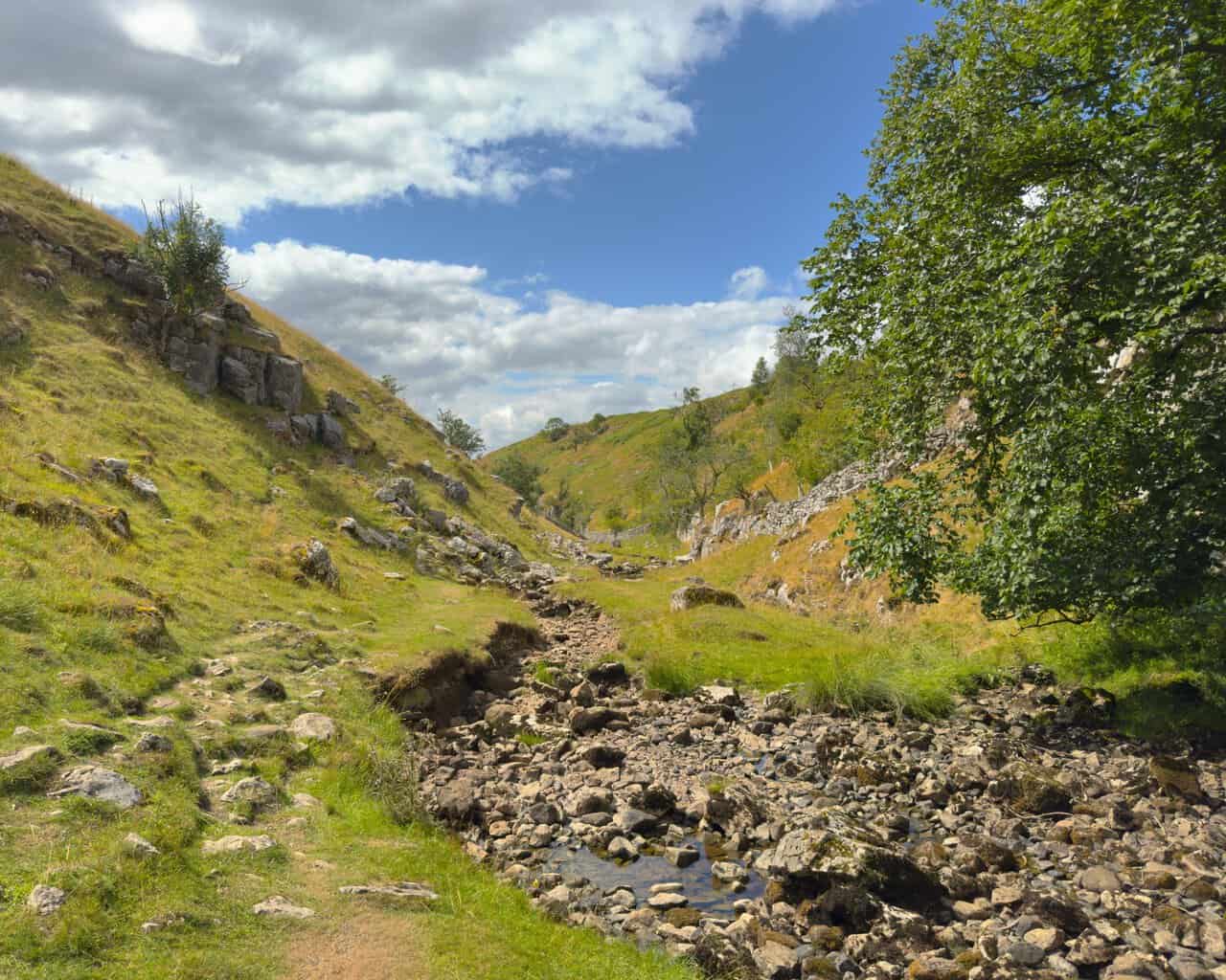 A wide bed of dry, bleached stones where the beck sinks underground at the entrance to the gorge.