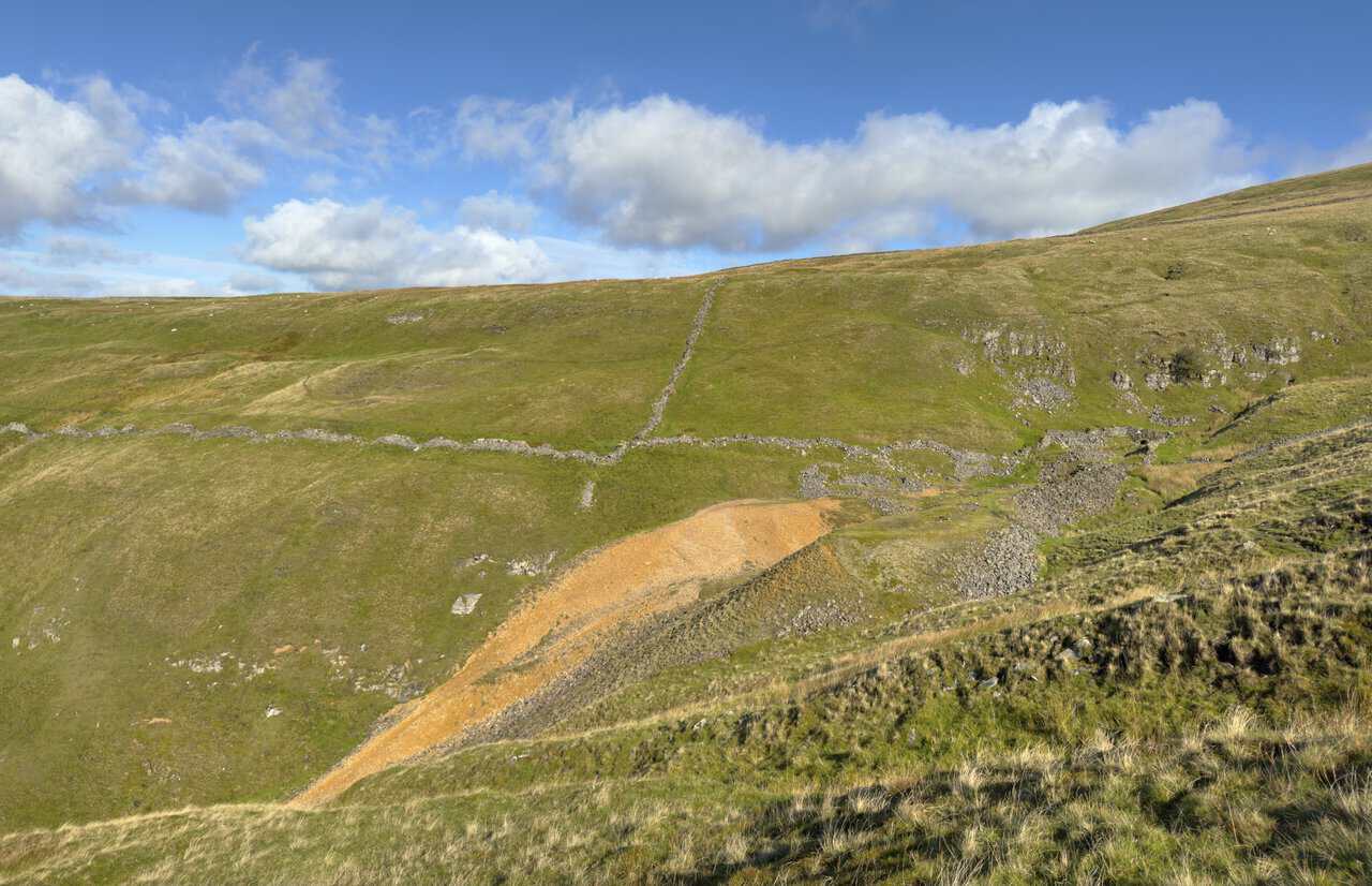 Orange spoil heaps and old stonework at the remains of Buckden Lead Mine.