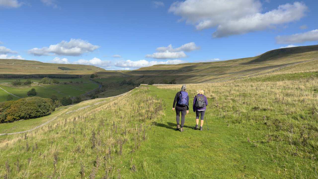Two walkers on the grassy track of Buckden Rake, heading north towards Cray.