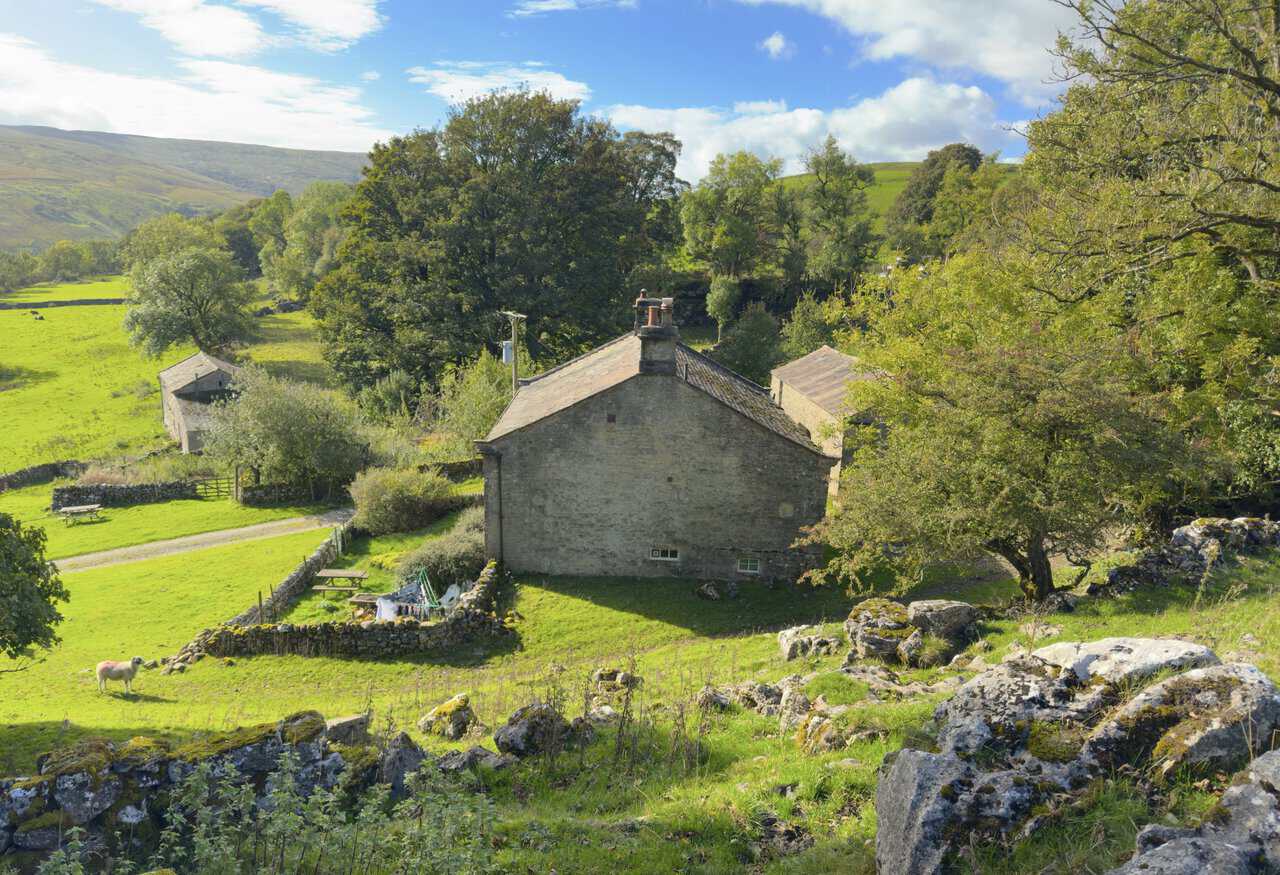 The rear of Scar House among trees and limestone boulders above Langstrothdale.