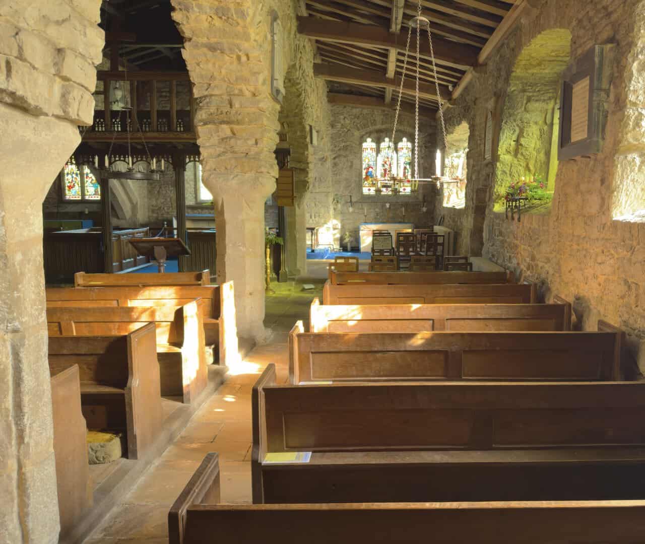 Sunlight falling on the wooden pews inside St Michael and All Angels Church, Hubberholme.