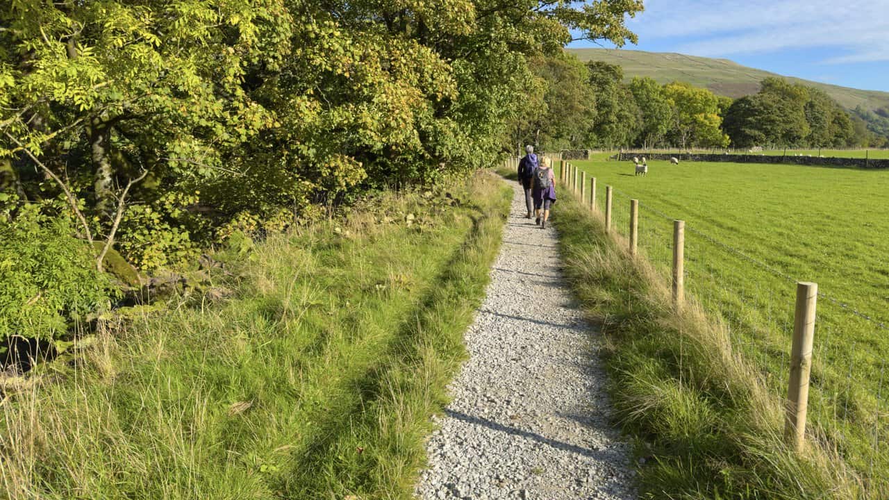 Two walkers on the gravel Dales Way path heading back to Buckden after crossing Buckden Pike.