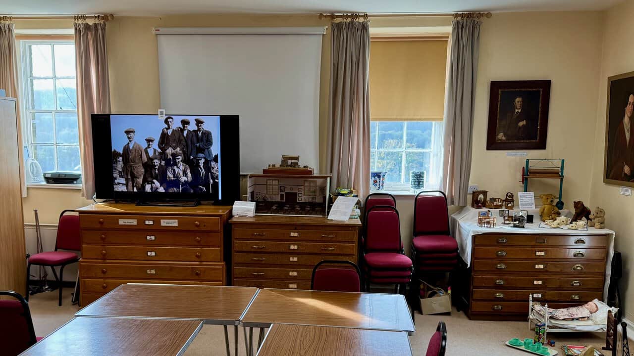 The study room at Nidderdale Museum, with numbered map drawers, a screen showing old photographs and a small model schoolroom.